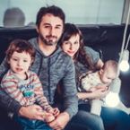 Happy family portrait: parents with two young children, one in arms, all smiling. Could represent the rewards of pressure washing your home and creating a clean, inviting space.
