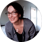 Smiling woman wearing glasses and a gray cardigan. This image can be used for a blog post about gutter cleaning or other home maintenance topics.